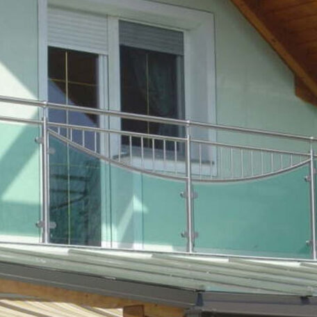 Moderner Balkon mit Glasgeländer und weißen Fenstertüren unter Holzvordach. HANSEL.kraus metalltechnik gmbh