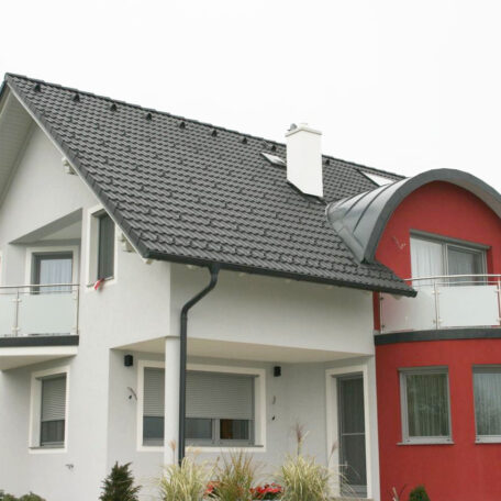 Modernes Einfamilienhaus mit Satteldach und rotem Fassadenakzent, Garten im Vordergrund. HANSEL.kraus metalltechnik gmbh