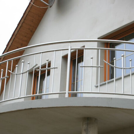 Moderner Edelstahl-Balkon mit geschwungener Brüstung an Einfamilienhaus, zwei Fenster im Hintergrund. HANSEL.kraus metalltechnik gmbh