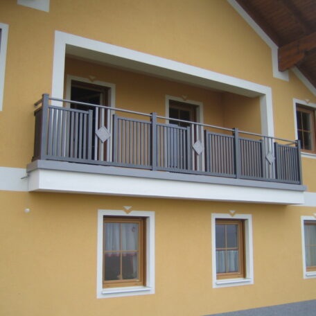 Moderner Balkon mit Metallgeländer an gelbem Haus, zwei Fenster darunter, Balkonbau Freiburg. de HANSEL.kraus metalltechnik gmbh
