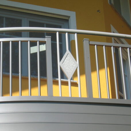 Geländer aus Metall mit Rautenmuster vor gelber Hauswand und Fenster auf Balkon. HANSEL.kraus metalltechnik gmbh
