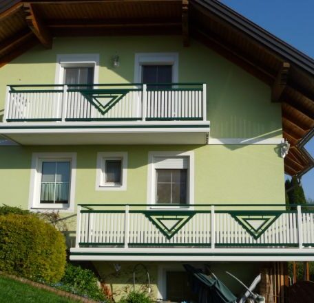 Zweistöckiges Einfamilienhaus mit grünem Balkon und Satteldach, umgeben von Garten. HANSEL.kraus metalltechnik gmbh