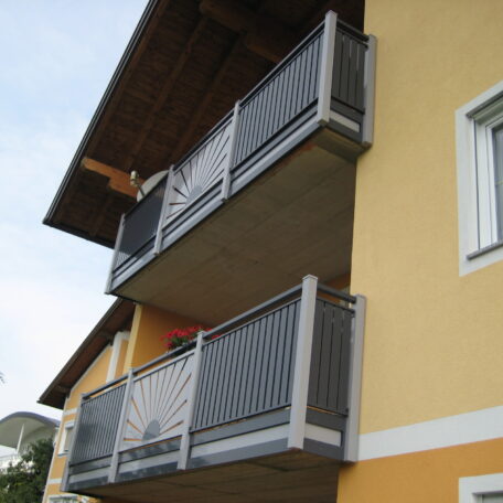 Zwei Balkone mit modernen Metallgeländern an gelber Hausfassade, darunter Fenster. de HANSEL.kraus metalltechnik gmbh