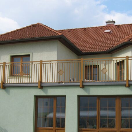 Zweistöckiges Haus mit Balkon, roten Dachziegeln und großen Fenstern, Tageslicht. HANSEL.kraus metalltechnik gmbh