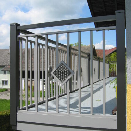 Metallgeländer mit Rautenmuster auf einer Rampe vor Wohnhäusern bei Tageslicht. HANSEL.kraus metalltechnik gmbh