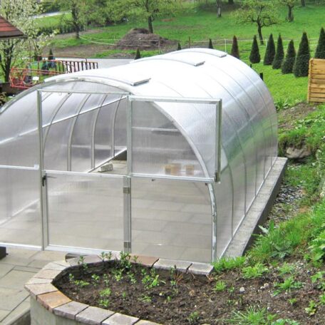 Modernes Gewächshaus aus Folie im Garten auf Betonfundament, umgeben von Pflanzen. de HANSEL.kraus metalltechnik gmbh