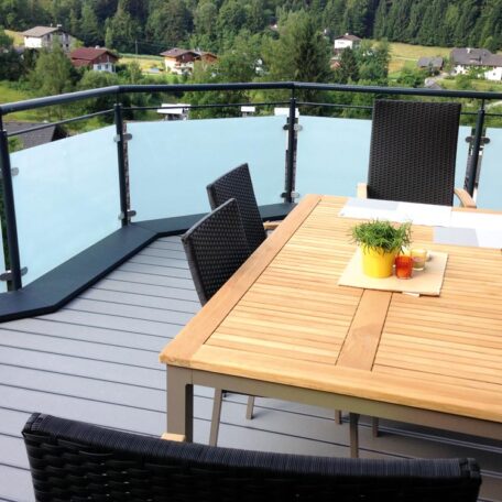 Moderner Balkon mit Holztisch, Stühlen und Glasgeländer vor grüner Landschaft, Freiburg. HANSEL.kraus metalltechnik gmbh