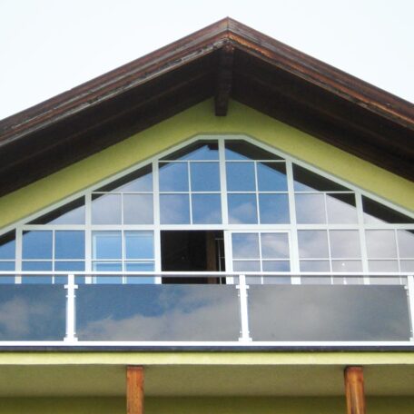 Großes Glasbalkonfenster mit reflektierendem Glas und Holzgiebel in moderner Hausfassade. HANSEL.kraus metalltechnik gmbh