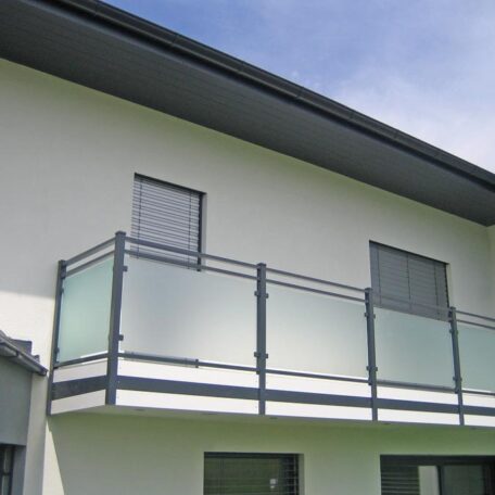 Moderner Balkon mit satinierten Glasscheiben an einem weißen Neubau unter blauem Himmel. HANSEL.kraus metalltechnik gmbh