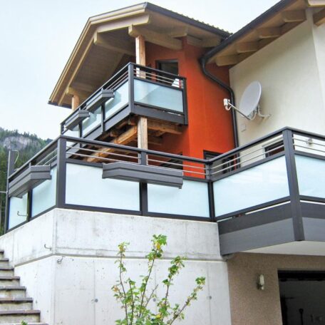 Modernes Haus mit satinierter Glasbrüstung und Außentreppe, Balkon im oberen Bereich, orange Wand. HANSEL.kraus metalltechnik gmbh