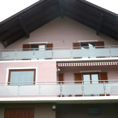 Dreistöckiges Wohnhaus mit breitem Balkon, moderner Verglasung und hölzernen Fensterläden. HANSEL.kraus metalltechnik gmbh