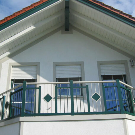 Balkon mit grünem Geländer und drei Fenstern an weißem Haus unter dem Dach. HANSEL.kraus metalltechnik gmbh