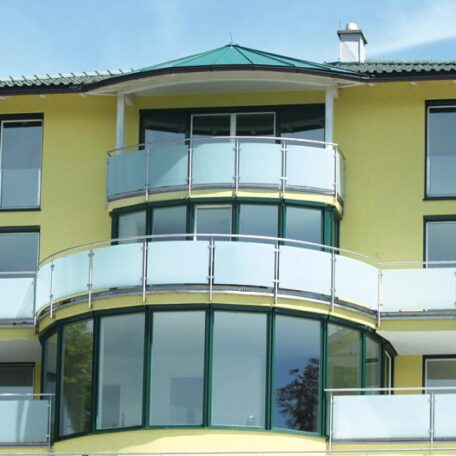 Modernes gelbes Wohngebäude mit großen Fenstern und halbrunden Balkonen, Außenansicht. HANSEL.kraus metalltechnik gmbh