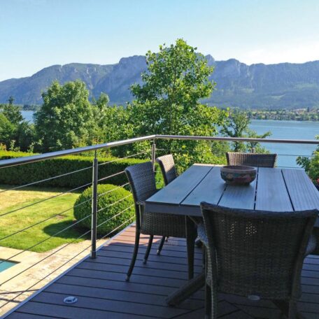 Moderne Terrasse mit Holztisch, Blick auf See und bewaldete Berge im Hintergrund. HANSEL.kraus metalltechnik gmbh