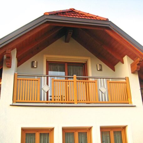 Balkon aus Holz mit Geländer an einem Einfamilienhaus unter rotem Satteldach. HANSEL.kraus metalltechnik gmbh