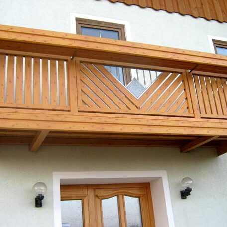 Holzbalkon mit modernem Geländer über Hauseingang, passende Holzverkleidung, zwei runde Wandlampen. de HANSEL.kraus metalltechnik gmbh