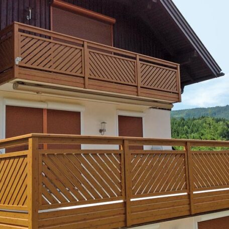 Balkon mit Holzgeländer an einem Haus vor bewaldeter Hügellandschaft, Außenansicht. de HANSEL.kraus metalltechnik gmbh