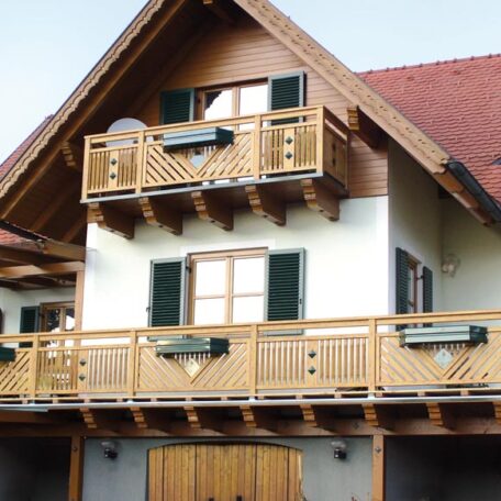 Zweistöckiges Einfamilienhaus mit Holzfassade, Satteldach, Balkon und grünen Fensterläden. HANSEL.kraus metalltechnik gmbh
