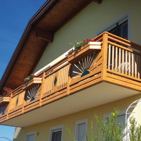 Holzbalkon mit Blumenkästen an gelbem Haus, sonniges Wetter, moderner Landhausstil. de HANSEL.kraus metalltechnik gmbh