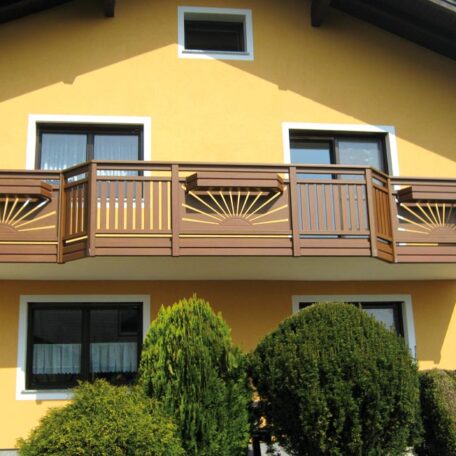 Zweistöckiges gelbes Haus mit Holzbalkon, drei Fenstern und gepflegten Sträuchern im Vordergrund. HANSEL.kraus metalltechnik gmbh