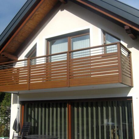 Modernes Einfamilienhaus mit Holzgeländer am Balkon, große Fenster und Schiebetüren im Erdgeschoss. HANSEL.kraus metalltechnik gmbh