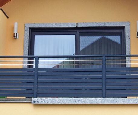 Moderner Balkon mit Glas-Schiebetür, grauem Geländer und gelber Fassade auf der Landingpage für Imagefilm-Produktion in Freiburg. HANSEL.kraus metalltechnik gmbh
