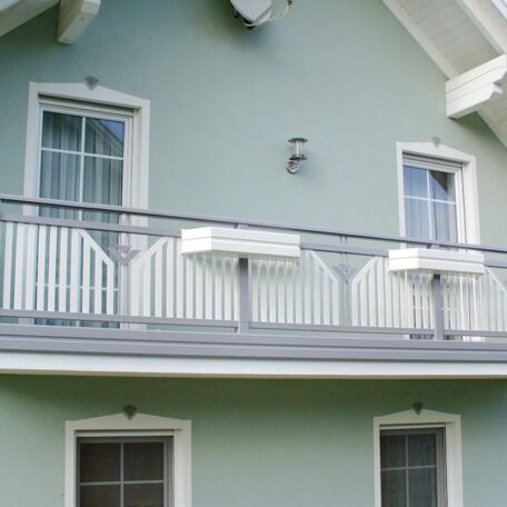 Zwei Fenster und ein weißer Balkon an einer hellgrünen Hausfassade. HANSEL.kraus metalltechnik gmbh