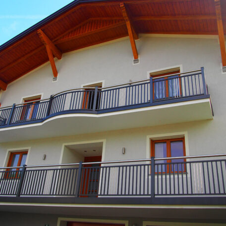 Modernes Mehrfamilienhaus mit Holzbalkon und Satteldach, drei Stockwerke, helle Fassade. HANSEL.kraus metalltechnik gmbh