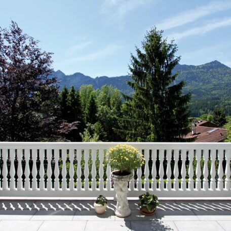 Blick von einer Terrasse auf Berge, Bäume und Hausdächer bei klarem Himmel. HANSEL.kraus metalltechnik gmbh