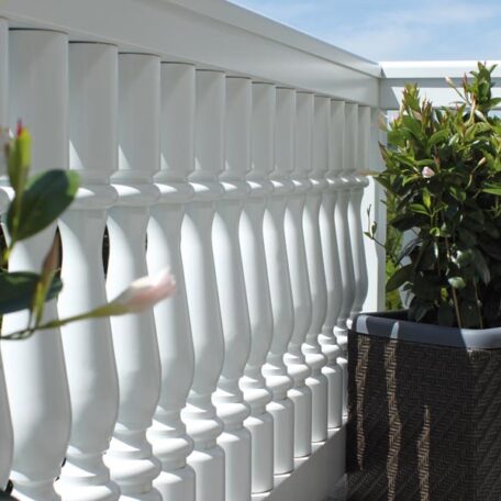 Weiße Balkonbalustrade mit Pflanzen im Topf und blauem Himmel im Hintergrund. HANSEL.kraus metalltechnik gmbh