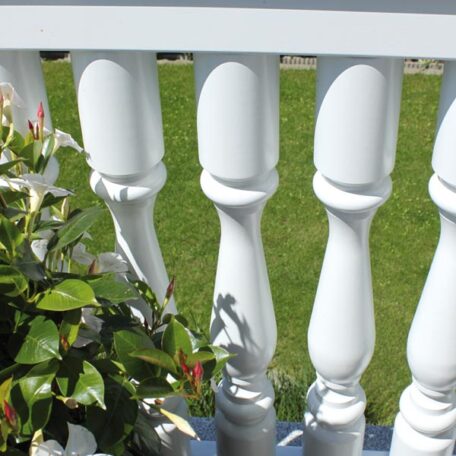Weiße Balkonbaluster mit Blumen am Rand und grünem Rasen im Hintergrund. HANSEL.kraus metalltechnik gmbh