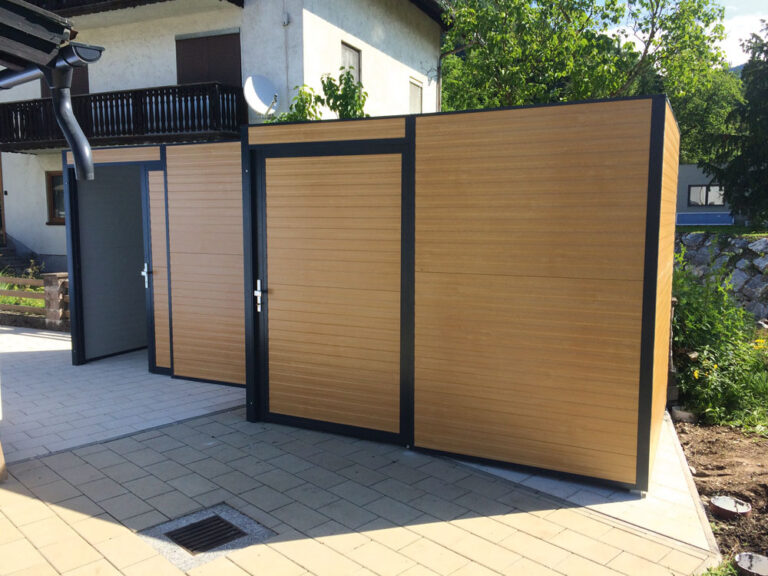 Moderne Mülltonnenbox aus Holz und Metall steht vor einem Haus im Sonnenschein. de HANSEL.kraus metalltechnik gmbh