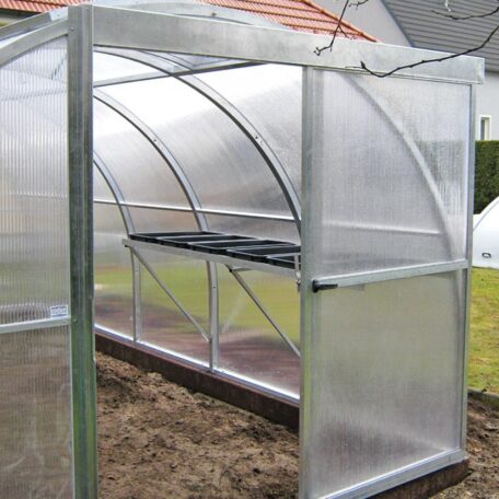 Gewächshaus aus Metall und Kunststoff mit geöffneter Tür steht auf einem Gartenboden. HANSEL.kraus metalltechnik gmbh