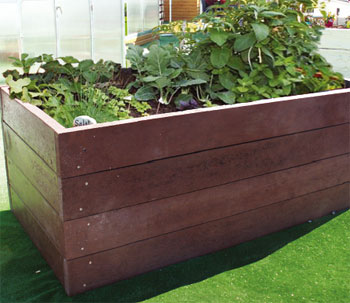 Hochbeet aus Holz mit verschiedenen Gemüsepflanzen auf grüner Rasenfläche. de HANSEL.kraus metalltechnik gmbh
