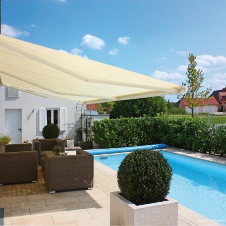 Moderne Terrasse mit Markise, Gartenmöbeln und Pool neben weißem Haus bei Sonnenschein. HANSEL.kraus metalltechnik gmbh