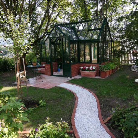 Gartenweg führt zu einem modernen Gewächshaus aus Glas mit Hochbeeten und Blumen. HANSEL.kraus metalltechnik gmbh