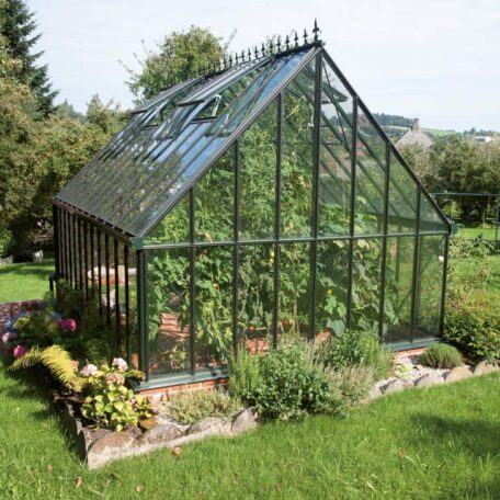 Glashaus im Garten mit üppigen Pflanzen, umgeben von Rasen und Blumenbeeten. de HANSEL.kraus metalltechnik gmbh