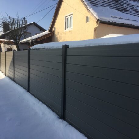 Moderner Gartenzaun vor Einfamilienhaus, beide von Schnee bedeckt, im Winter. Sprache: de HANSEL.kraus metalltechnik gmbh