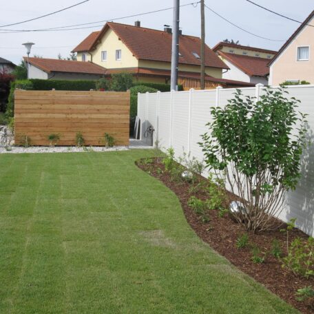 Gepflegter Garten mit grünem Rasen, Blumenbeeten und Zaun in Wohnsiedlung, sonniger Tag. HANSEL.kraus metalltechnik gmbh
