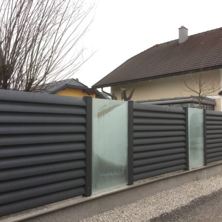 Moderner Gartenzaun aus Metall und Glas vor Einfamilienhaus, trennend zur Grundstücksgrenze. Sprache: de HANSEL.kraus metalltechnik gmbh