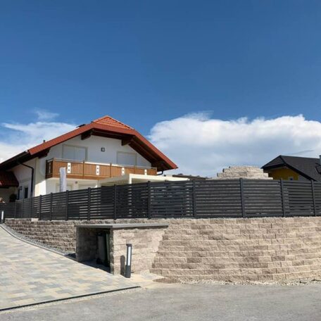 Modernes Einfamilienhaus mit Steingarten, Sichtschutzzaun und rotem Dach an sonnigem Tag. de HANSEL.kraus metalltechnik gmbh