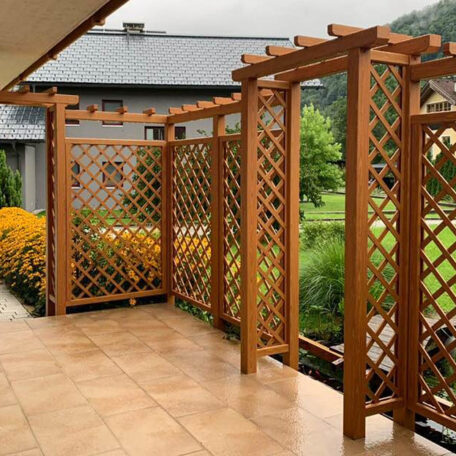 Holzpergola mit Rankgittern auf einer Terrasse, im Hintergrund Garten und Haus, Sommerwetter. HANSEL.kraus metalltechnik gmbh