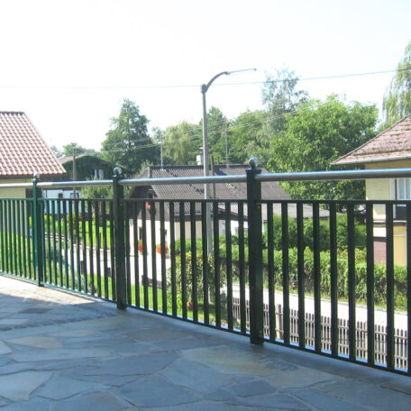 Große Terrasse mit schwarzem Metallgeländer und Blick auf Wohnhäuser sowie grüne Bäume. HANSEL.kraus metalltechnik gmbh