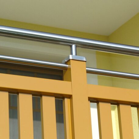 Gelbes Balkongeländer mit Edelstahlhandlauf vor gelber Wand auf moderner Gebäudefassade. de HANSEL.kraus metalltechnik gmbh