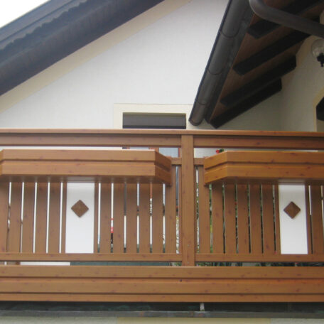 Holzbalkon mit schrägem Dach und weißen Wandelementen an Wohnhausfassade. HANSEL.kraus metalltechnik gmbh