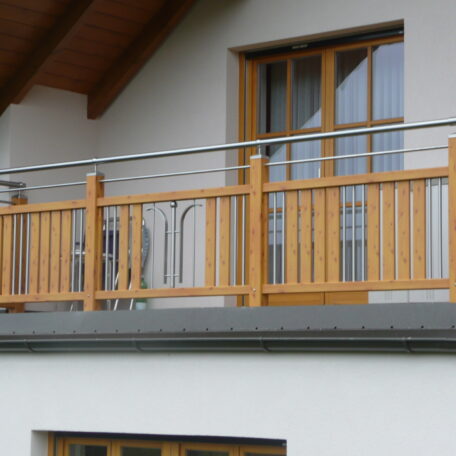 Balkon mit Holzgeländer und großen Fenstern unter einem Dachvorsprung, modern gestaltet. HANSEL.kraus metalltechnik gmbh