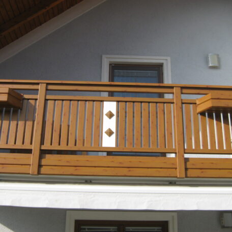 Holzbalkon mit verziertem Geländer vor Fenster an Hausfassade, Tageslicht, moderner Stil. HANSEL.kraus metalltechnik gmbh