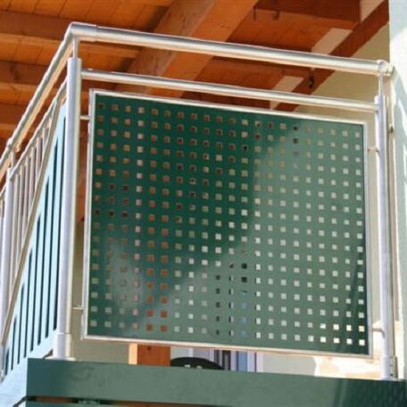 Balkongeländer aus Metall mit grünem Lochblech, darüber ein Holzdach, im Hintergrund Hausfassade. HANSEL.kraus metalltechnik gmbh