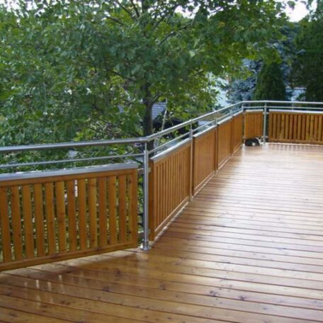 Große Holzterrasse mit Metallgeländer, umgeben von Bäumen, auf einer Landingpage für Imagefilm-Produktion in Freiburg. HANSEL.kraus metalltechnik gmbh