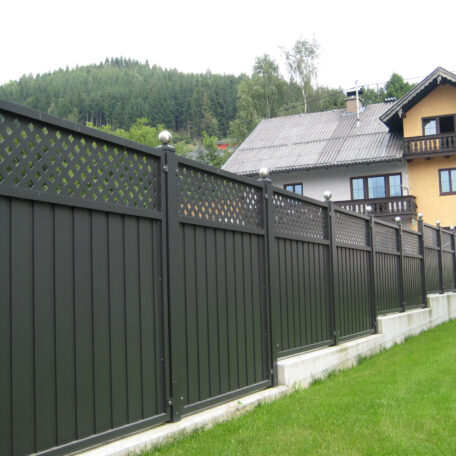 Moderner Sichtschutzzaun aus Aluminium trennt gepflegten Garten von Wohnhäusern in ländlicher Umgebung. de HANSEL.kraus metalltechnik gmbh